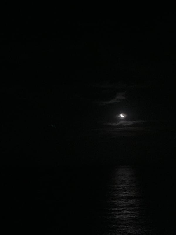 Nighttime maritime observation captures moonlit crane, compass, distant lights