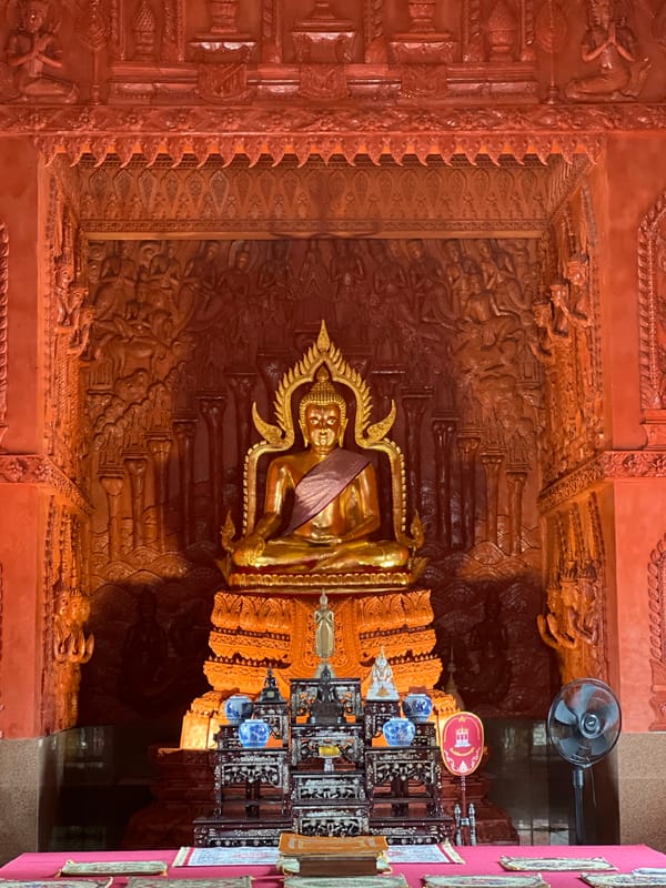 Golden Buddha in purple sash glows inside Ko Samui shrine