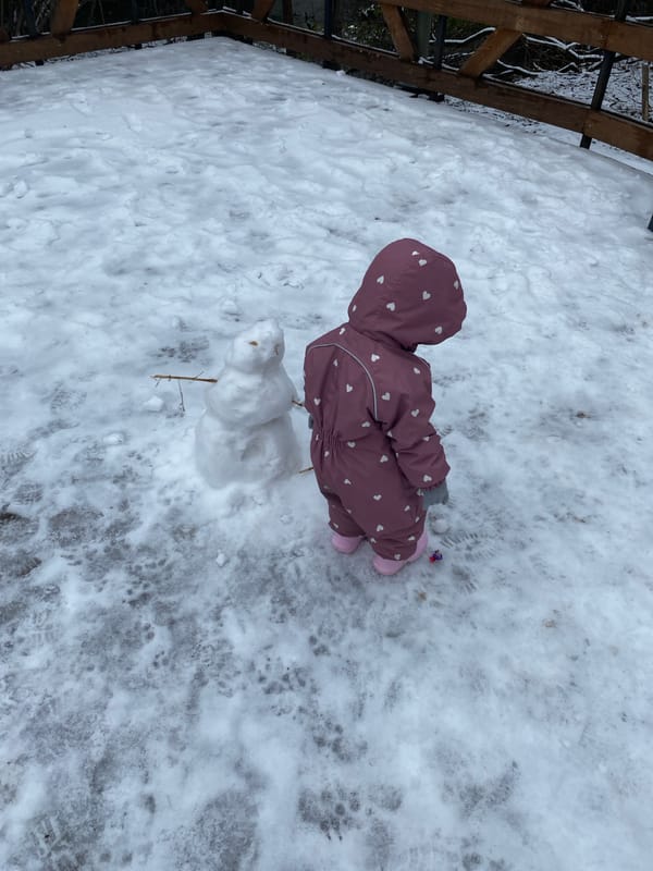 Child plays in snow wearing pink snowsuit in Perm