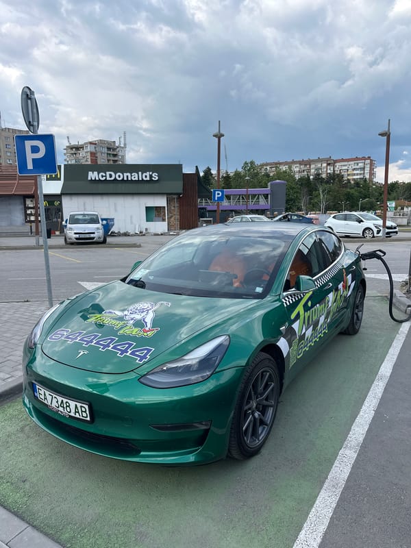 Green Tesla taxi charges outside McDonald's in Bulgarian city