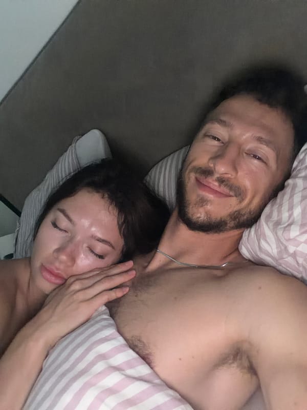 Two people resting in bed, shot from above indoors.