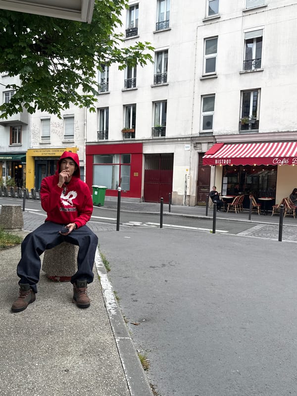 Person in red hoodie sits on concrete structure in Paris