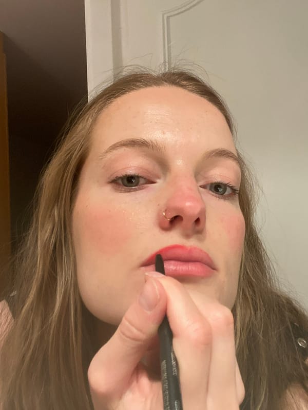 Woman applies red lip liner with eyeliner pencil in Paris