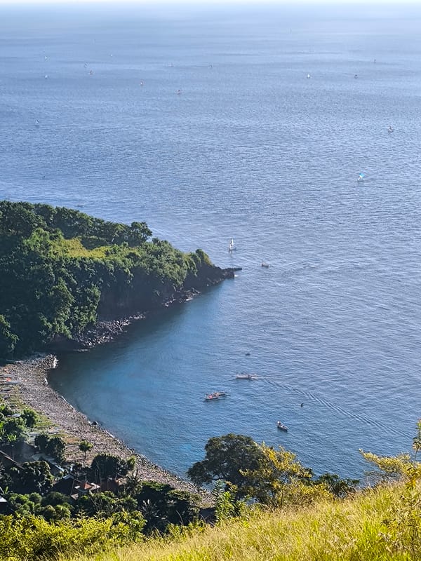 Indonesian coastal village observed with colorful sailboats in cove