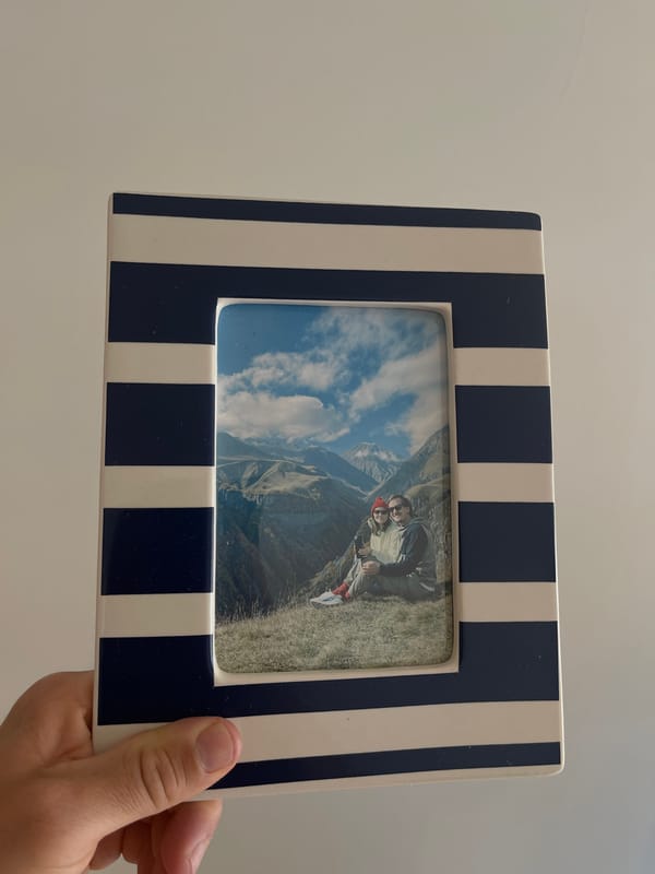 Person holds framed photo of couple in mountains