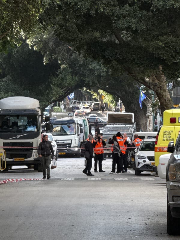 Man in yarmulke skateboards past stationary trucks in Ramat Gan