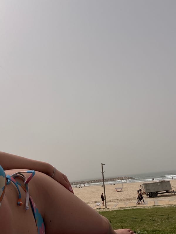 Beachgoer relaxes on overcast day at Herzliya beach