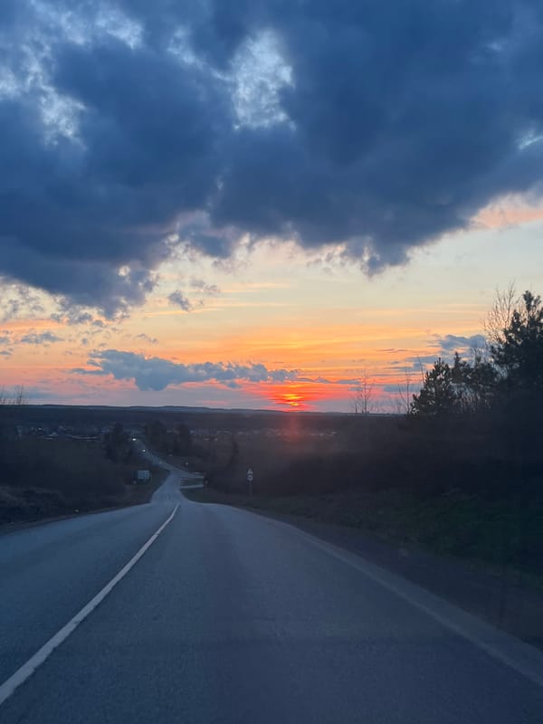 Sunset road scene contrasts storm clouds with vibrant skies