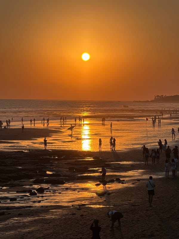 Sunset crowds, coastal rocks, and ceremony on Bali's west shore