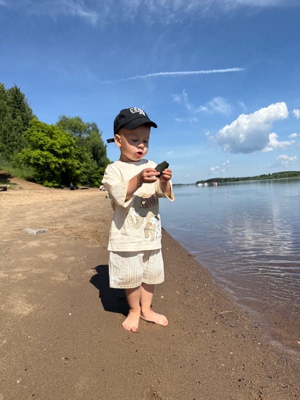 Boy with dark object stands on beach