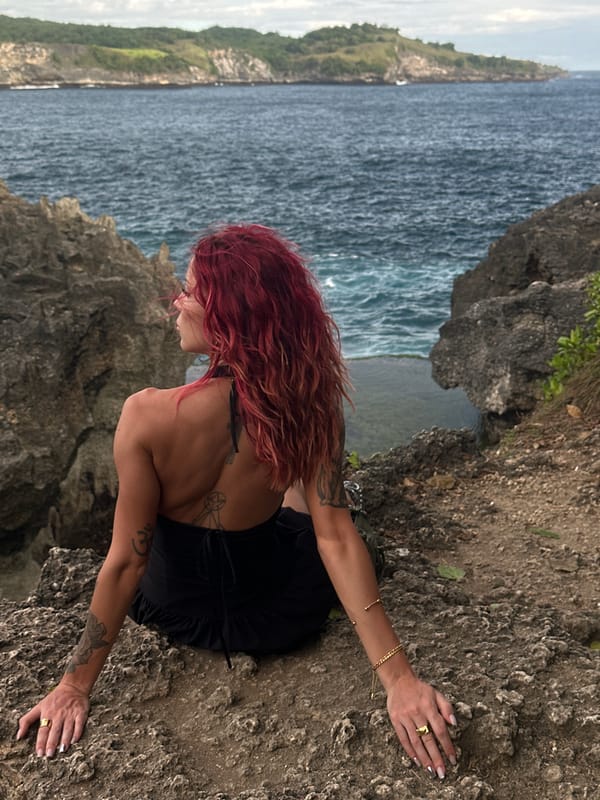 Tourist photographs red-haired woman at Nusa Penida cliffs