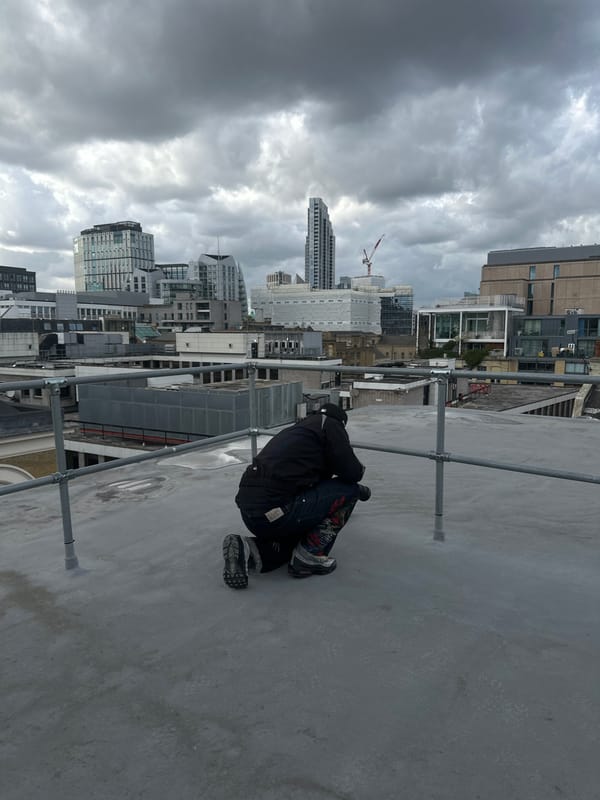 Person observed on London rooftop viewing cityscape during overcast afternoon