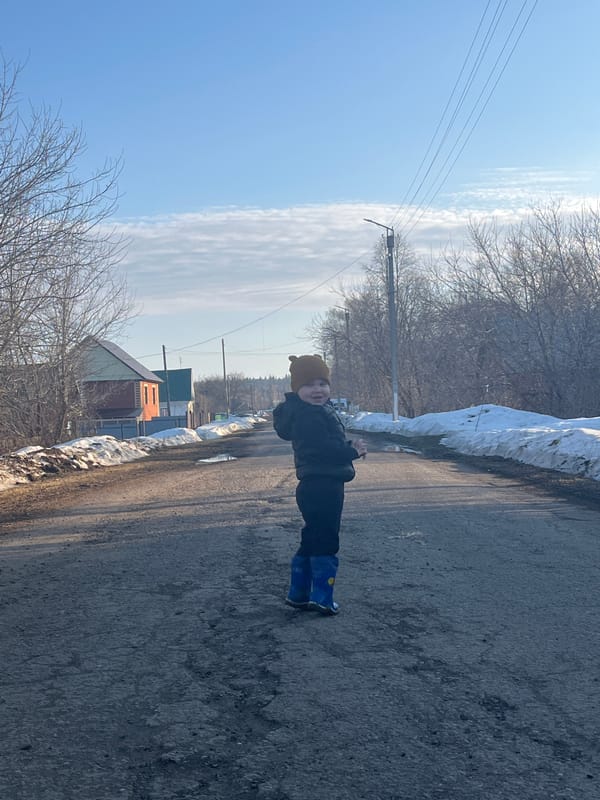 Child walks with dog on snowy street in Павловка