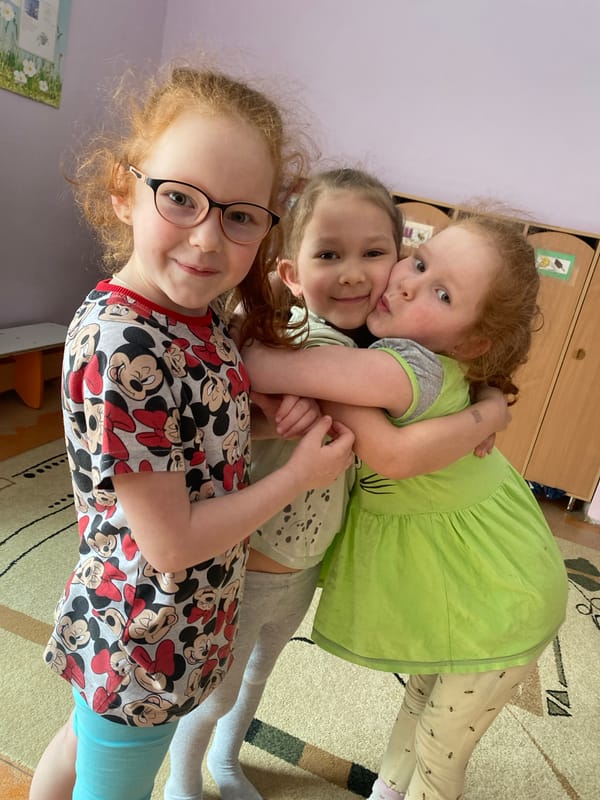 Three girls pose affectionately indoors in Izhevsk, Russia