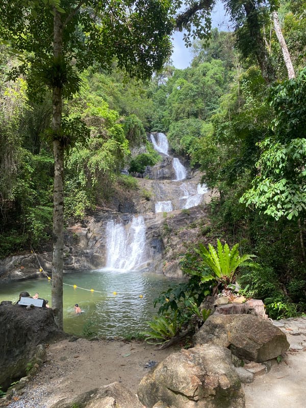 Tourist visits Thai Mueang waterfall attraction, documents nature experience