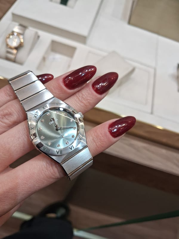 Silver watch with diamond markers spotted on burgundy-nailed hand