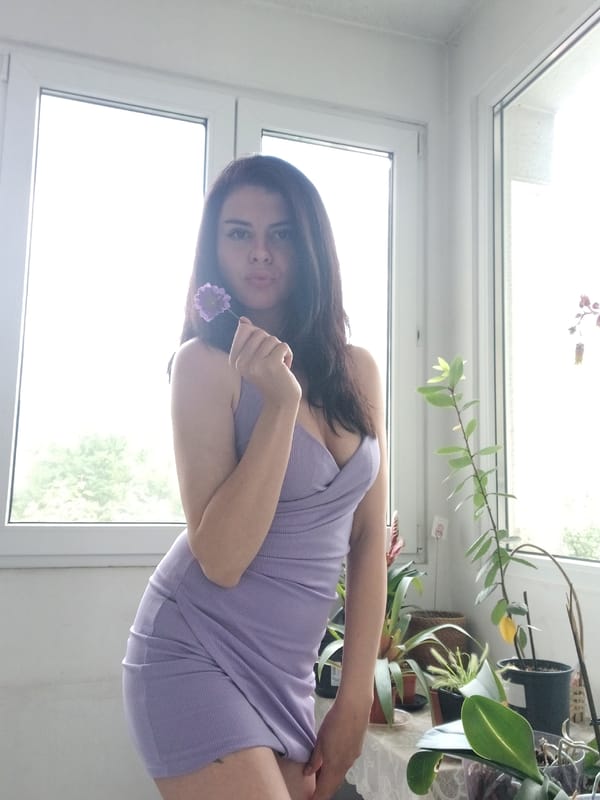 Woman poses with purple flower in Sofia apartment
