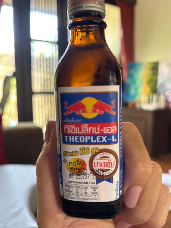 Person holds Thai energy drink with red bulls logo