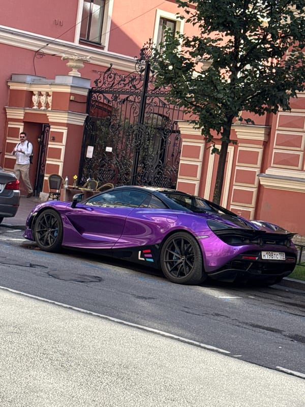 Purple McLaren 720S parked outside classical Saint Petersburg building