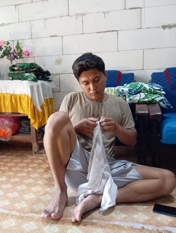 Man rests on wooden bench indoors in Baron, Indonesia