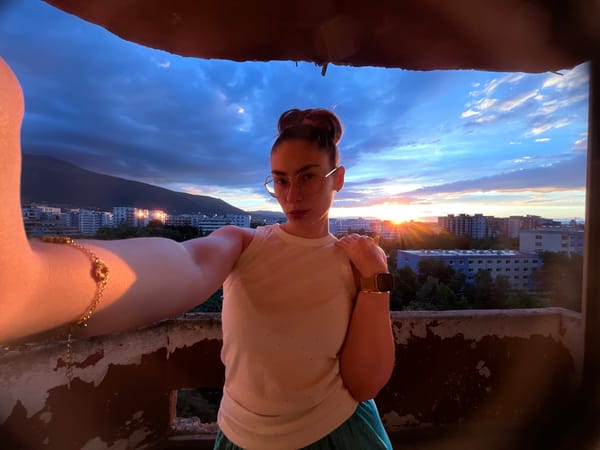 Woman captures sunset selfies from city balcony during golden hour