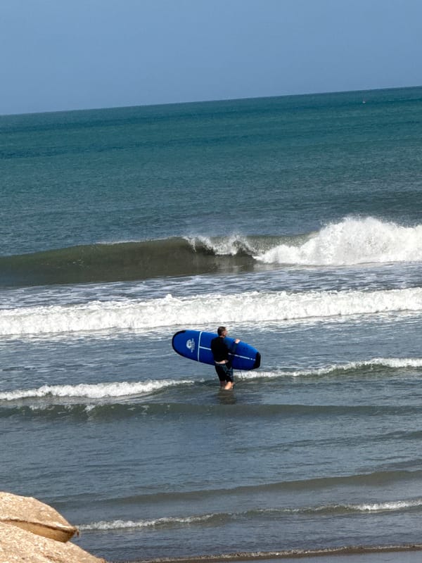Surfers and beachgoers moving along Kuta Beach, Bali