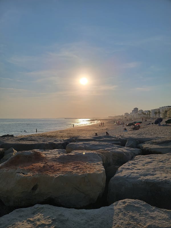Sunset along Quarteira's rocky coastline with a yacht offshore
