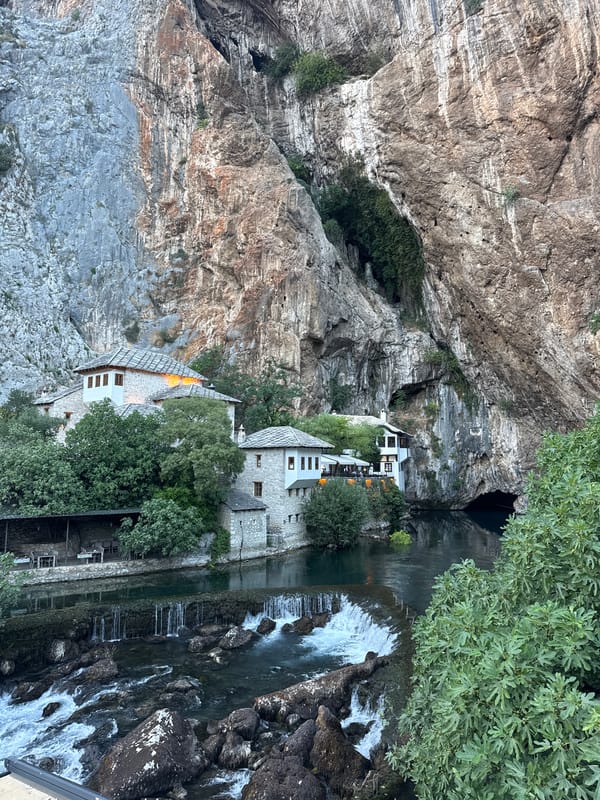 Stone village architecture nestled beneath cliffs in rural Bosnia