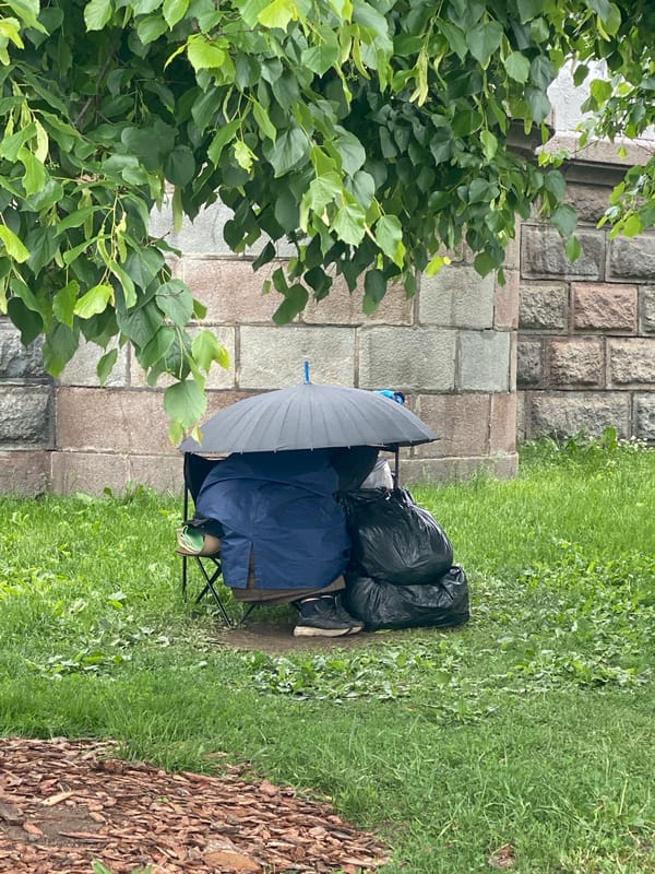 Person sits under umbrella by stone wall in Moscow