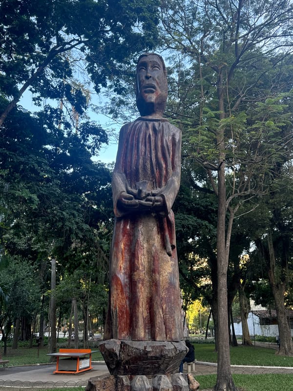 Niterói park square with giant trees, wildlife, and wooden sculpture