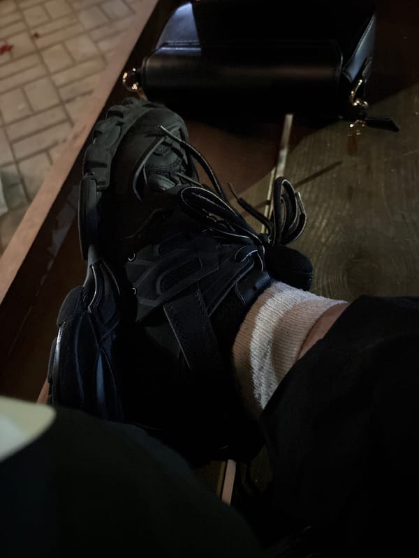 Black athletic shoe photographed on wooden surface indoors