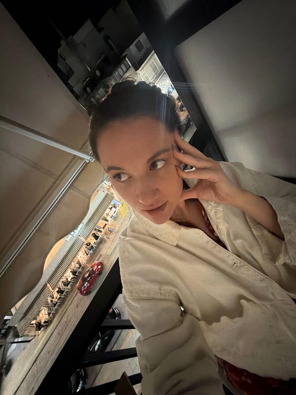 Woman photographs herself on Glifada balcony evening