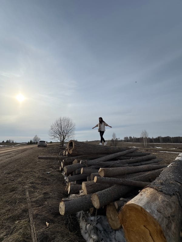 Woman poses on log pile in rural Van'ki field