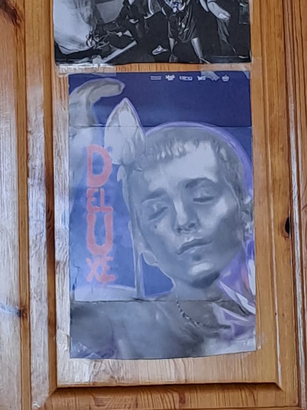 Two posters displayed on wooden surface at unknown location