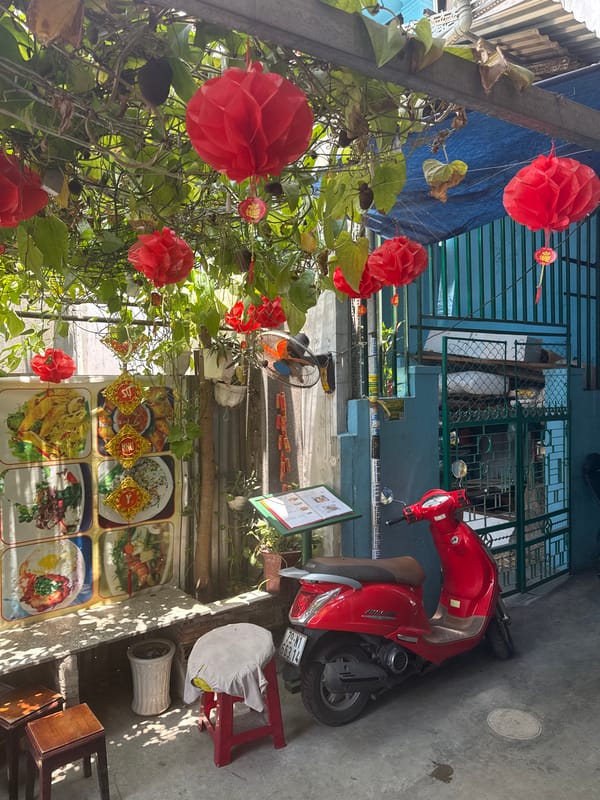 Street-side business with green foliage, red decorations captured
