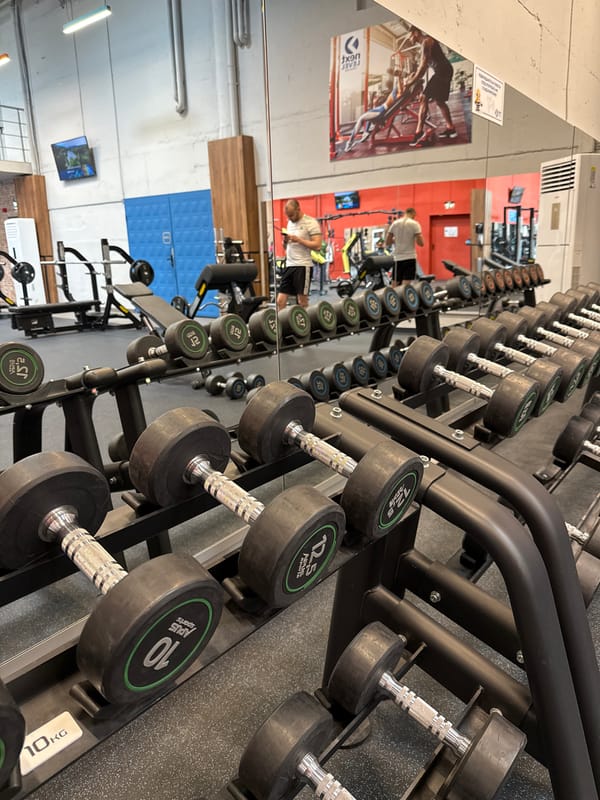 Person selects dumbbells at Sofia gym weight rack