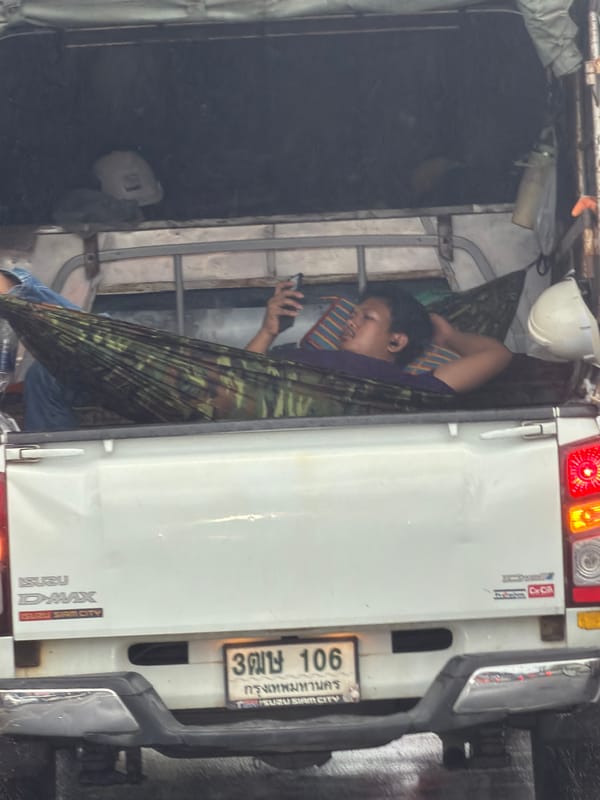Man relaxes in hammock inside pickup truck bed in Thailand