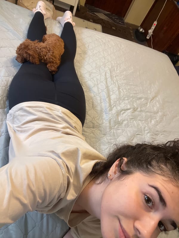 Woman rests with poodle on bed in Sofia