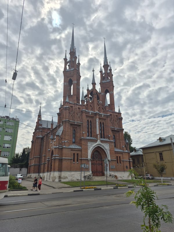 Twin-spired brick church in Novokuybyshevsk under cloudy skies