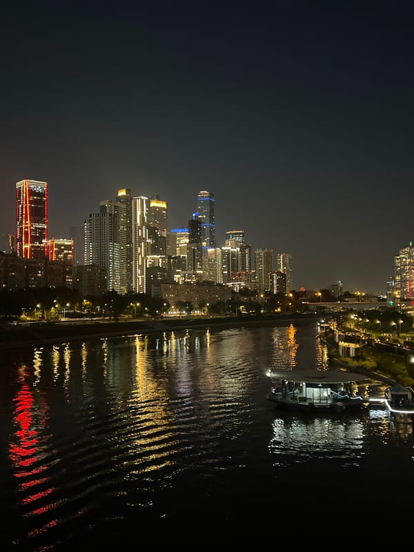 Glittering city skyline reflects across a wide river at night