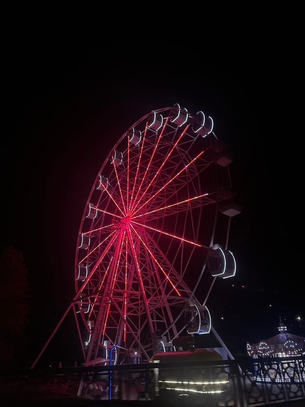 New Athos landmarks, waterfall, and fairground lights at dusk