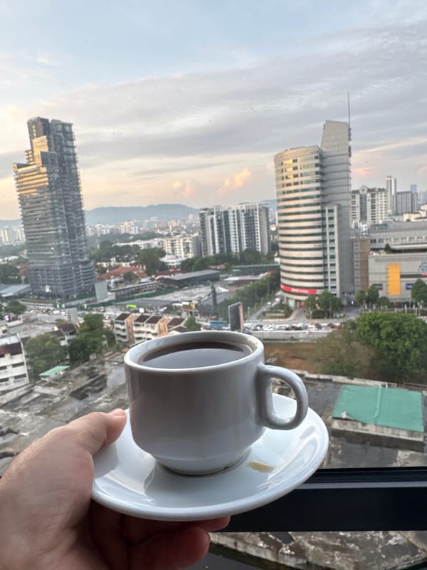 KL skyline at dusk, coffee in hand, city lights below
