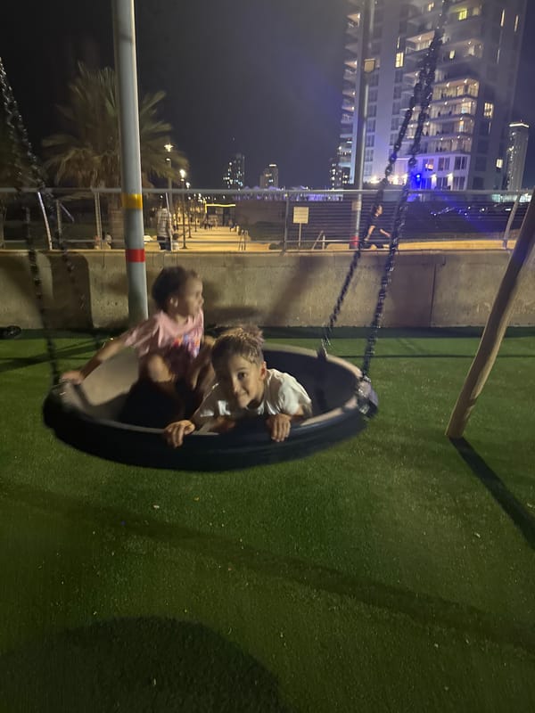 Kids on a tire swing, summer evening playground fun in Netanya