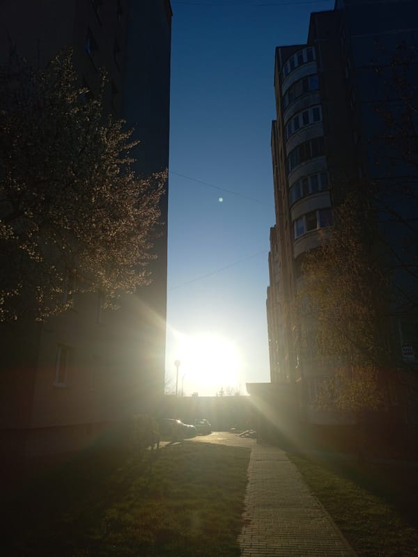 Morning sunlight illuminates urban pathway between buildings in Hrodna