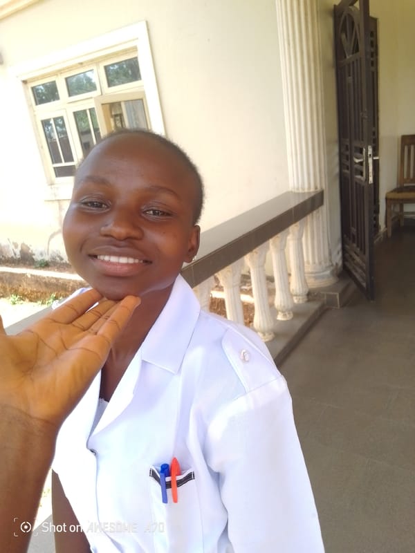 Healthcare worker photographed smiling outdoors in white uniform