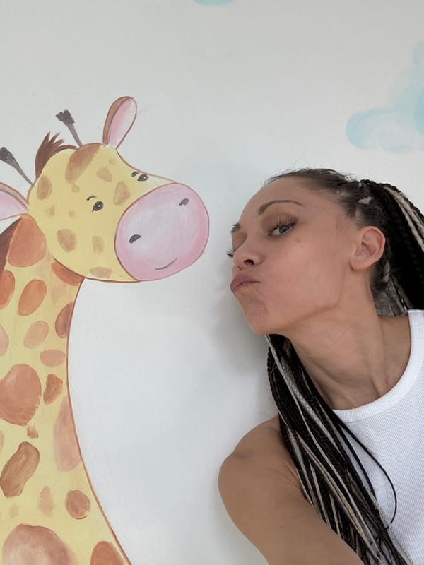 Woman and child play with water near giraffe mural