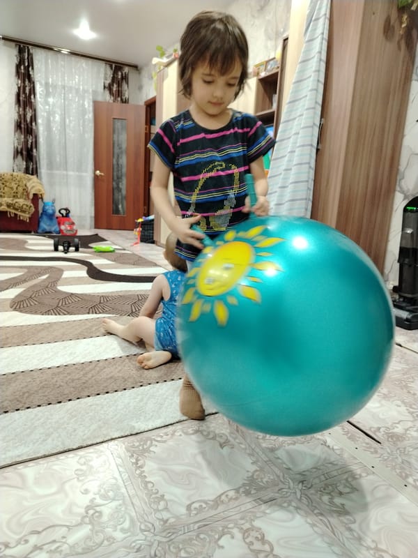 Children play with inflatable ball at home in Russia