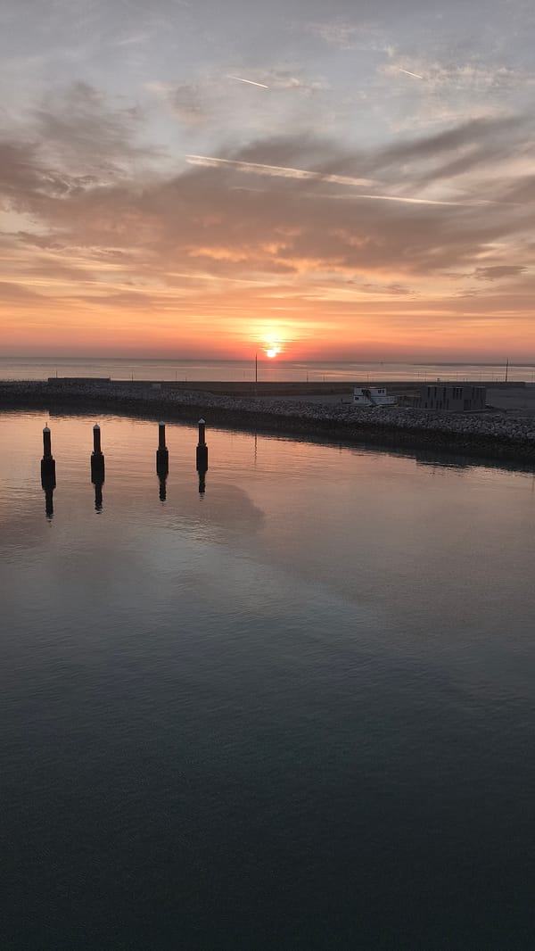 Sunrise over Calais harbor, warm light on still water