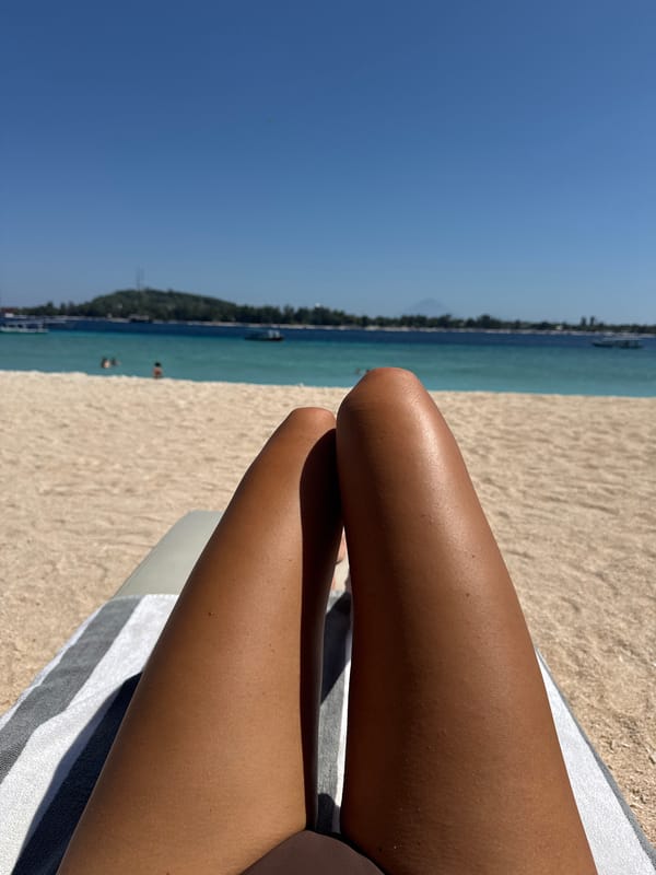 Woman sunbathes on striped towel at Indonesian beach