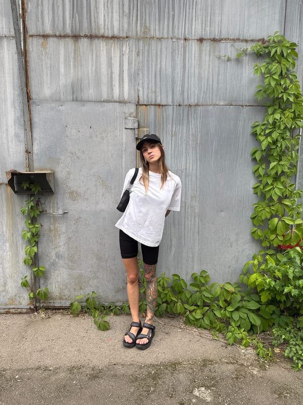 Tattooed figure poses against rusty corrugated wall in Moscow